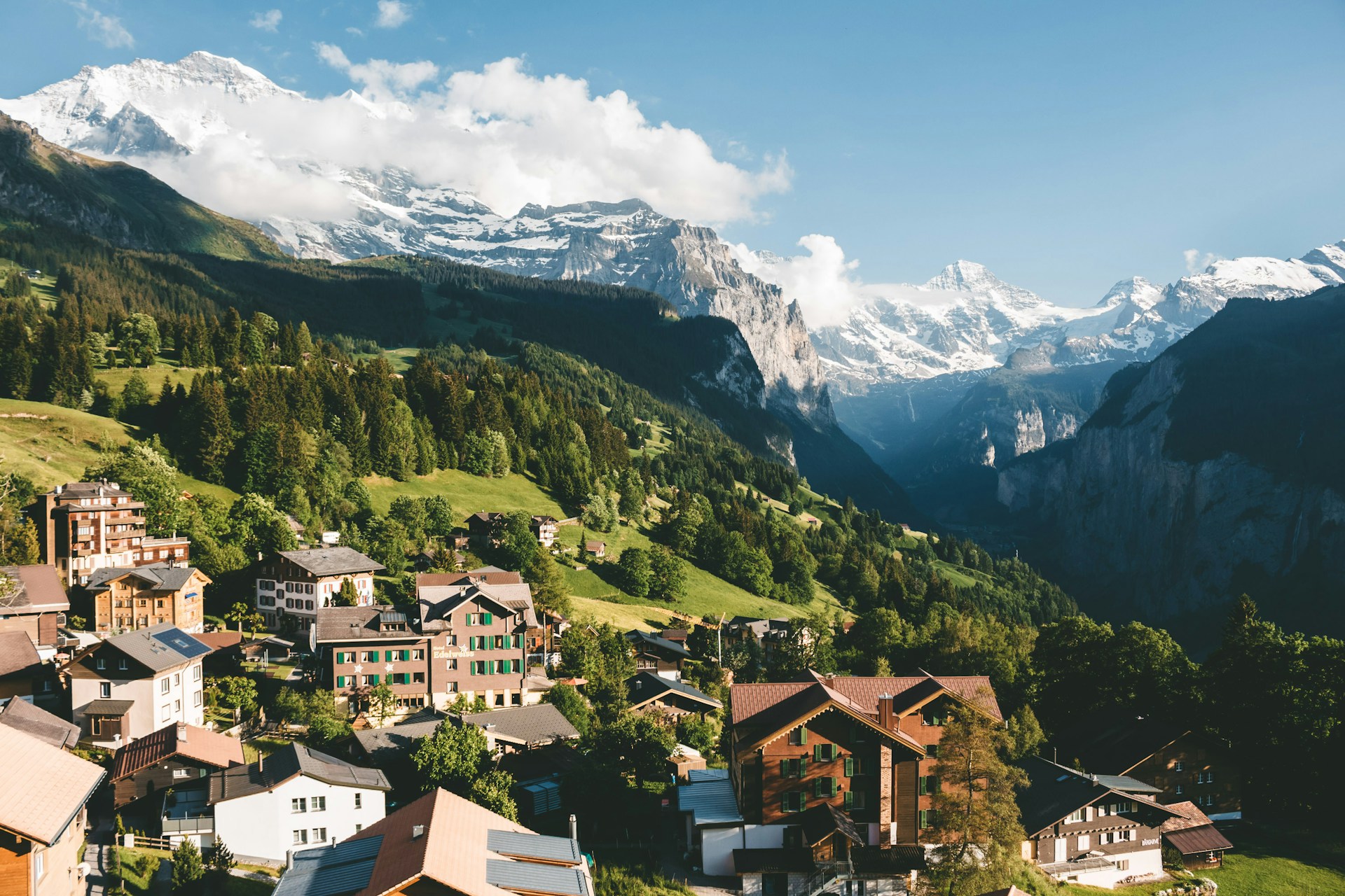 A town high in the mountains with snowy mountain peaks in the background during daytime.