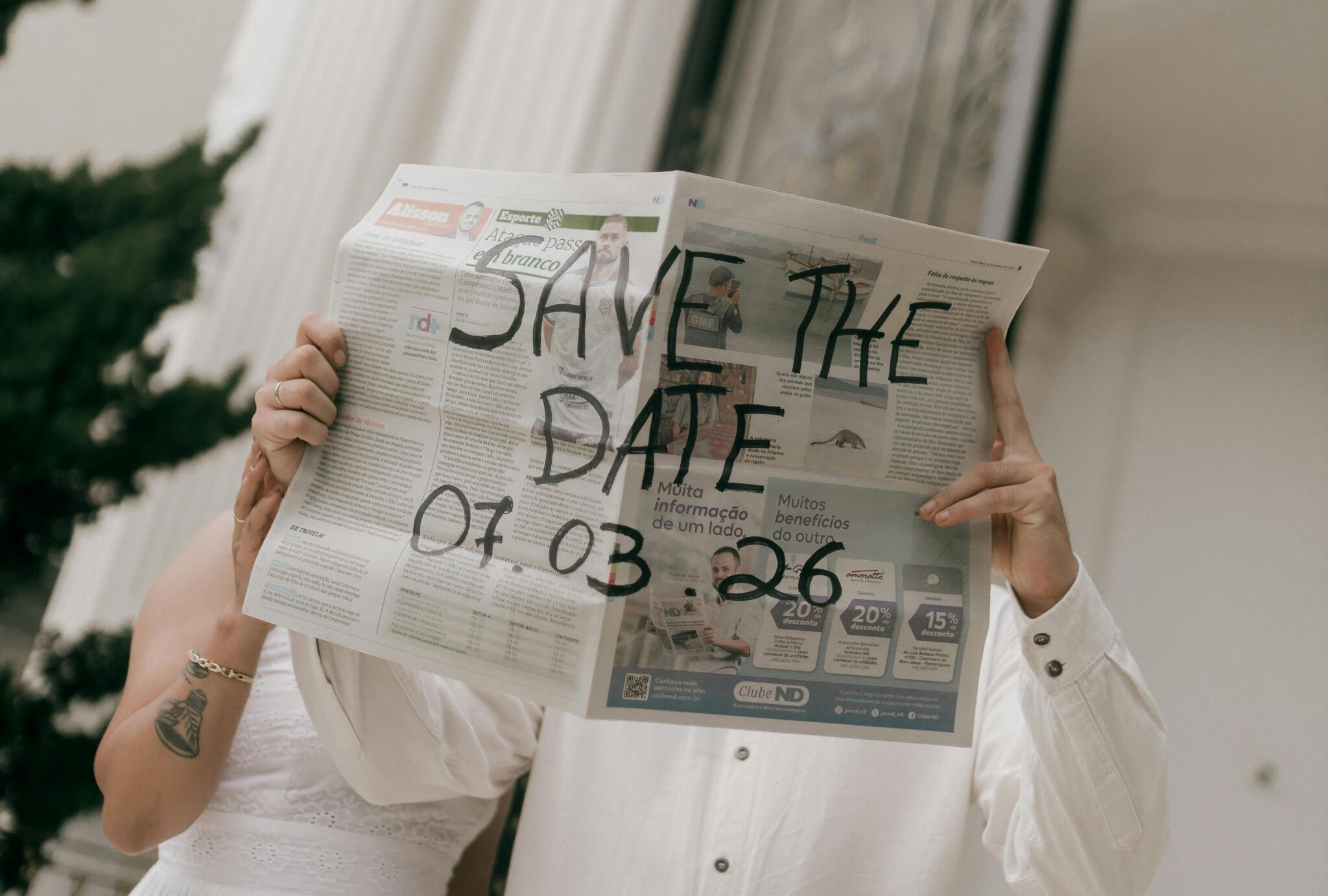 A couple holding up a "save the date" newspaper.
