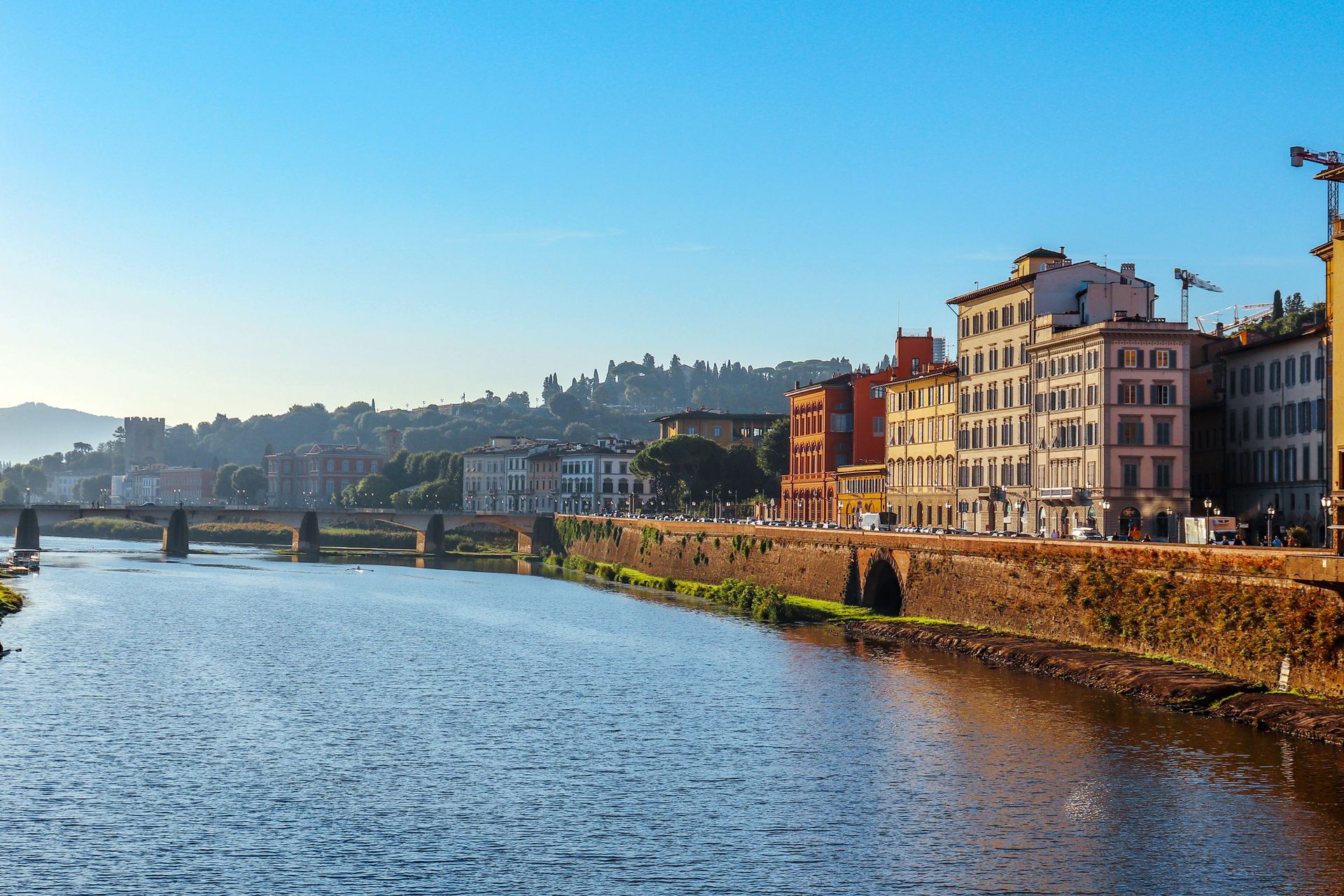 Scenic daytime view of the Arno River with historic buildings in Florence, Italy.