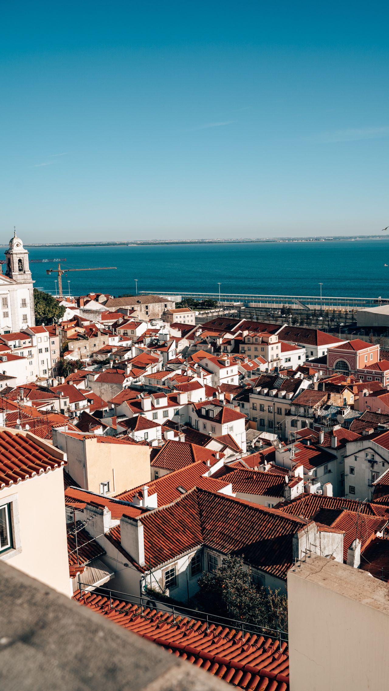 View over city of Lisbon with orange tile roofs and an ocean view.